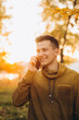 © anatoliycherkas - Portrait of handsome and happy guy smiling and talking on the phone in the autumn park