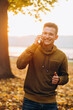© anatoliycherkas - Portrait of handsome and happy guy smiling and talking on the phone in the autumn park