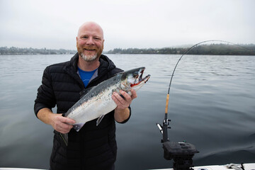 Man holds fresh caught wild Coho Salmon fish