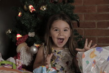Happy Girl Child Of Brazilian Origin Near A Christmas Tree With Gifts Around