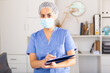 © JackF - Woman in protective mask is standing with documents in clinic