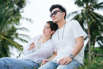 asian couple traveler sitting together on the beach.