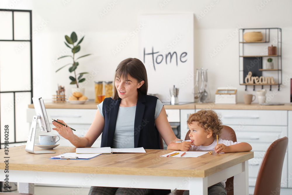 Working mother with little son in kitchen at home
