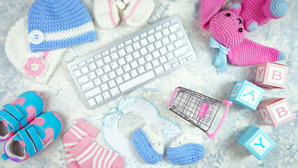 Wall Mural - Baby nursery clothing mom bloggers desktop workspace with pink and blue accessories and shopping cart on white marble textured background. Top view blog hero header creative composition flat lay.
