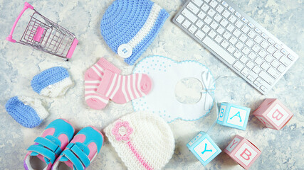 Wall Mural - Baby nursery clothing mom bloggers desktop workspace with pink and blue accessories and shopping cart on white marble textured background. Top view blog hero header creative composition flat lay.