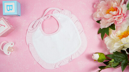 Wall Mural - Baby bib nursery clothing mom bloggers desktop mockups with peonie floers on pink textured background. Top view blog hero header creative composition flat lay. Negative copy space mock up.