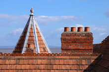 Old Brick Chimney Pots On A Victorian Building Roof Against A Blue Sky Background