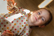 Little girl lies on the wooden floor in the morning sun