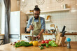© Svitlana - Young man, chef cook using hand blender while preparing Italian meal in the kitchen