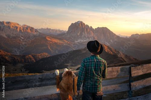 Fotomural a man with a red dog looking at the mountains