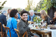 © Trinette Reed/Stocksy - Portrait of mature Hispanic man with group of friends enjoying a Farm To Table Dinner Party in backyard