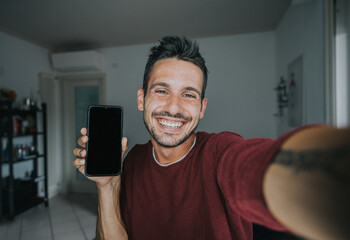 Handsome millennial man taking a selfie with smartphone holding and showing a cell phone with empty black screen. People and technology.