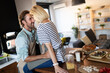 © NDABCREATIVITY - Beautiful young couple is talking and smiling while cooking healthy food in kitchen at home