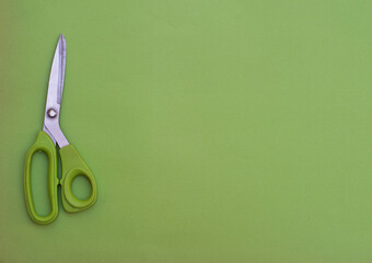 Wall Mural - Green scissors on green background