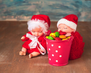 Two Santa crumbs are sitting by a colored bucket with a pocket