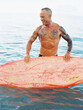 © wendy laurel/Stocksy - handsome ripped athletic senior man with surfboard at ocean