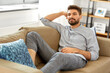 © Syda Productions - people and leisure concept - young man sitting on sofa at home