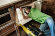 © W2 Photography/Stocksy - Handyman working on sink in the kitchen