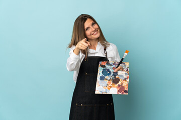 Young artist Slovak woman isolated on blue background pointing front with happy expression