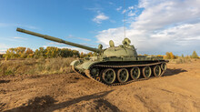 A Side Shot Of Old Russian Tank T-62 In The Field. Blue Cloudy Sky As A Background.