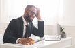 © Prostock-studio - Tired black businessman drinking alcohol at workplace