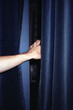 © Di Na/Stocksy - Hand and blue velvet blackout curtains