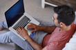 © Trinette Reed/Stocksy - Young hispanic man working from home in his pajamas in the bedroom