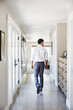 © Trinette Reed/Stocksy - Young man walking down a hallway in a modern luxury home