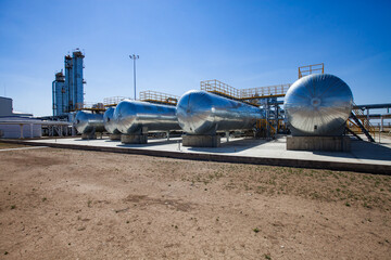 Oil refinery and gas processing plant in desert. A few heat exchangers and distillation towers (refinery columns) on blue sky with sun.