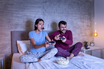 Wall Mural - Couple having fun playing video games in bed