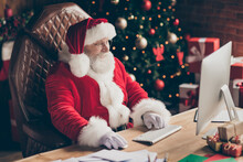Profile Side Photo Of Santa Claus Sit Table Desk Work Computer Before X-mas Christmas Night Midnight Check Email Read Kids Gift Present Wish List In House Indoors Wear Cap Headwear