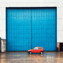 Red Car Infront Big Blue Doors