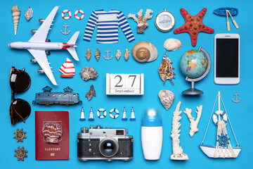 Happy world tourism day. Touristic objects, smart phone, passport, photo camera, sunglasses and decorative items on blue background. Flat lay, top view. Calendar date September 27, world tourism day