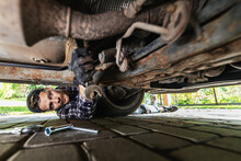 Man Repairing Bottom Of Rusty Old Car. Mechanic Working