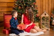 Mom and son sort out Santa's gifts under the Christmas tree. Family holidays, Christmas tale. Best childhood memories