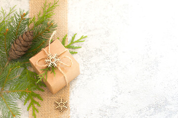 Christmas composition. Christmas gift, jute, pine cone and fir twigs on light background