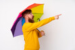 © luismolinero - Redhead man with long beard holding an umbrella over isolated white background pointing finger to the side