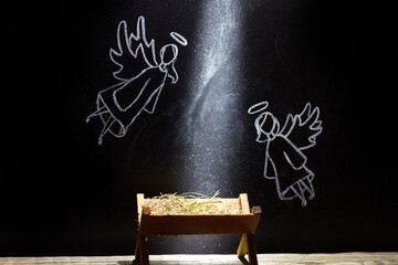 Birth of Jesus, manger and angels on blackboard abstract christmas nativity scene