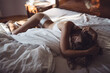 © AD Photography/Stocksy - Young woman in underwear lying on bed