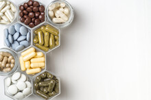 Various Capsules And Pills With Dietary Supplements Or Medicines In Hexagonal Jars
