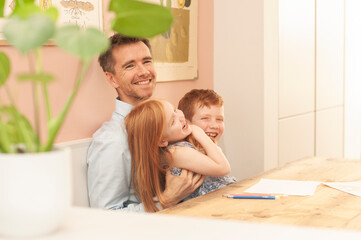 Authentic picture of dad, pre-teen boy and young girl laughing during homeschooling due to the coronavirus lockdown. Landscape format.