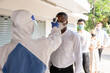 © godji10 - Selective Focus. A medical worker in hazmat suit using thermometer to check the employee before work on a business day that covid-19 coronavirus is epidemics. Security measures of new normal life.