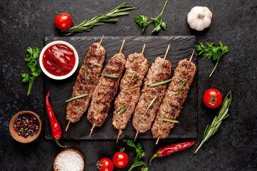 Wall Mural - grilled Lula kebab on skewers with spices on a stone background

