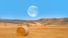 Big Round Bales Of Straw In The Meadow With Full Moon - Harvested Field With Straw Bales In Summer "Elements Of This Image Furnished By NASA"