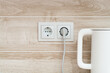 © skiminok - White electric power sockets on wall background with plugged electric kettle into a kitchen, copy space.