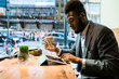 © simon/Stocksy - Young black businessman working in a cafe