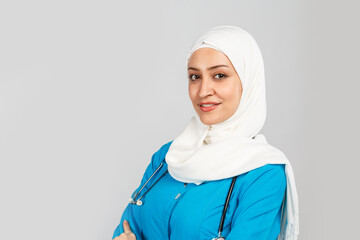 beautiful modern muslim doctor or nurse in hijab on a gray background. blue uniform.