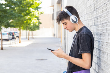 Poster - male teenager with mobile phone and headphones in the city