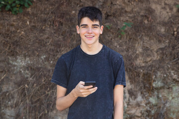 Wall Mural - portrait of teenage boy with mobile phone outdoors