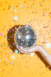 © CACTUS Creative Studio/Stocksy - Hand holding a disco mirrors ball with confetti